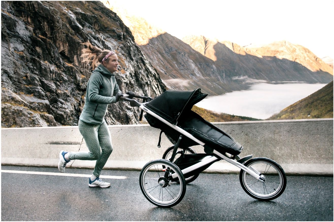 A woman runs down a mountain path with one of the best strollers for running