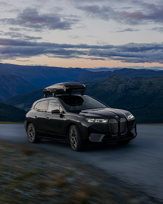 Um SUV circula por uma estrada ao anoitecer com uma caixa de teto Thule no topo.