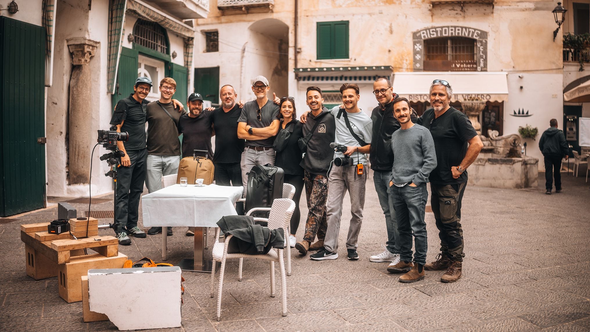 Die Filmcrew steht Arm in Arm nebeneinander und lächelt in die Kamera, um einen erfolgreichen Drehtag zu feiern.
