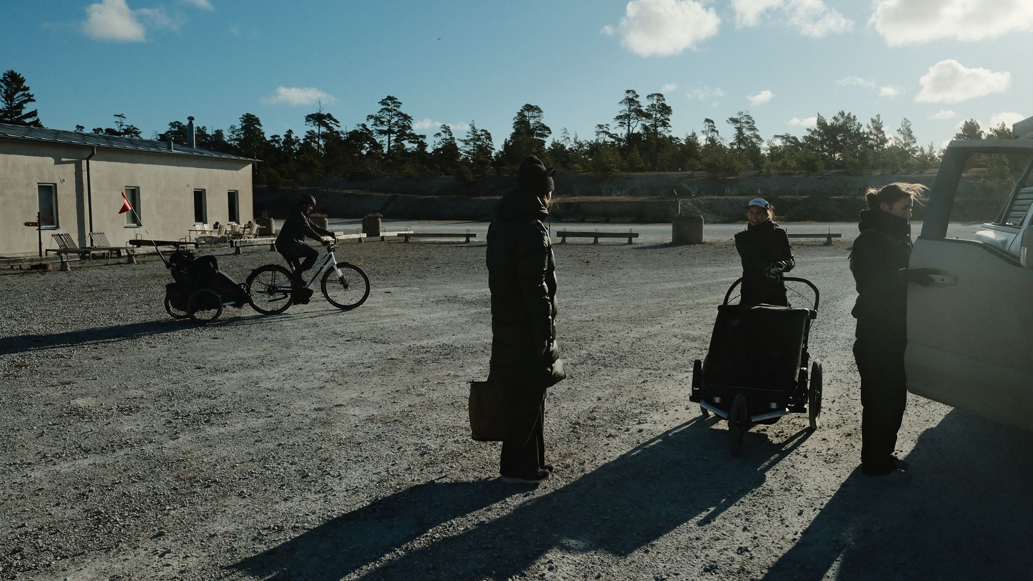 Nos bastidores da campanha A Different Kind of Strong da Thule, com membros da equipe, um carrinho de bebê Thule e um ciclista reunidos em uma área aberta de cascalho.