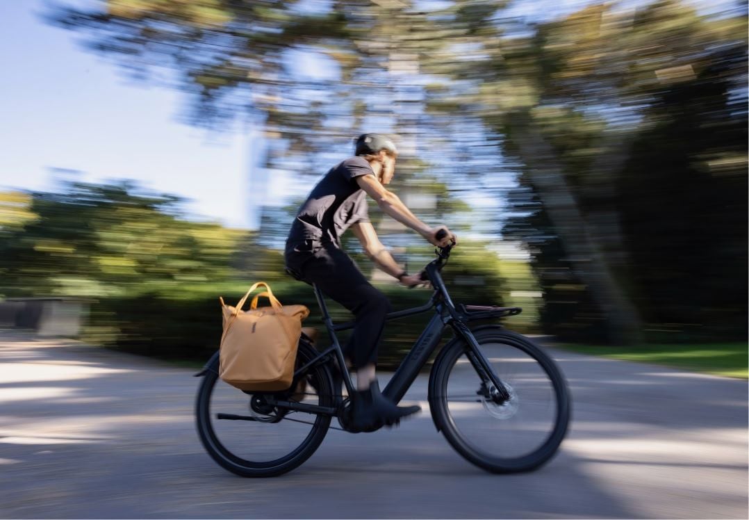Cyclist riding with a bag secured by the InLock pannier system by Thule.