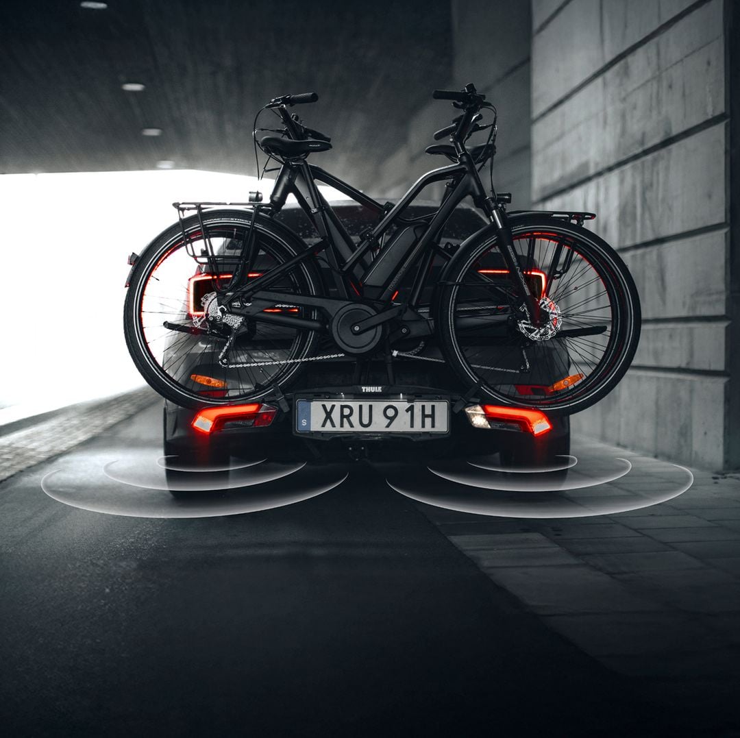 Zwei Fahrräder, die auf einem Thule Epos-Fahrradträger auf der Rückseite eines Autos montiert sind, das durch einen Tunnel fährt.