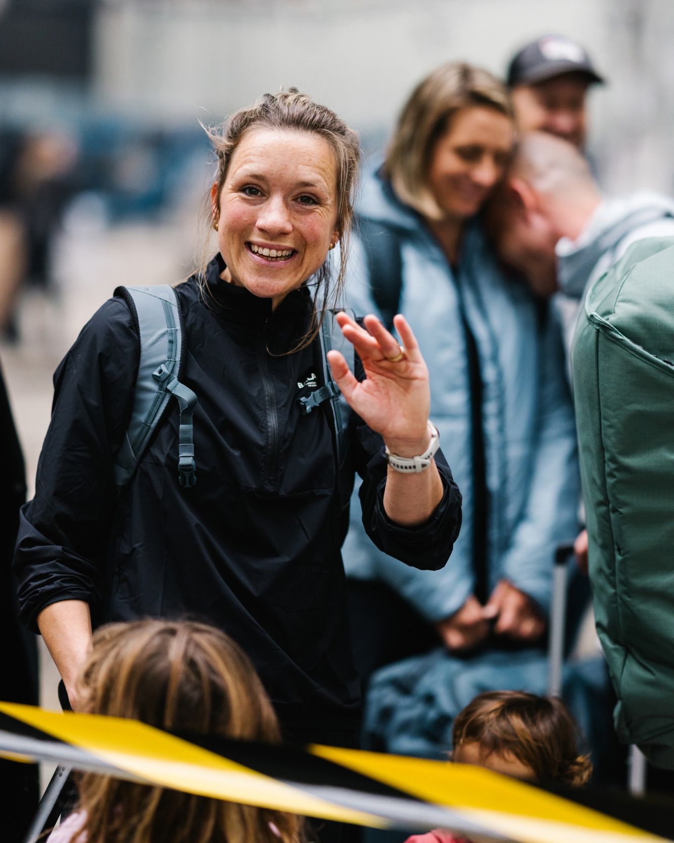 A person waving while standing among a crowd.