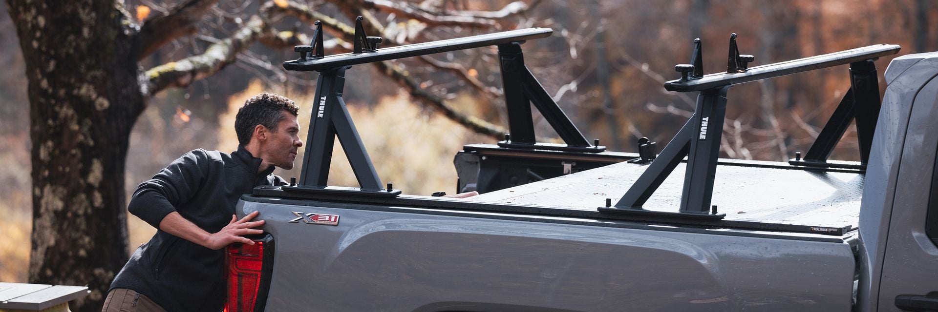 Person loading gear onto a pickup truck with a Thule Xscape truck rack.