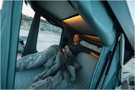 Woman in a rooftop tent enjoying the view