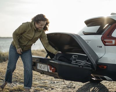 A woman reaches into a rear cargo box and pulls out a cargo duffel.