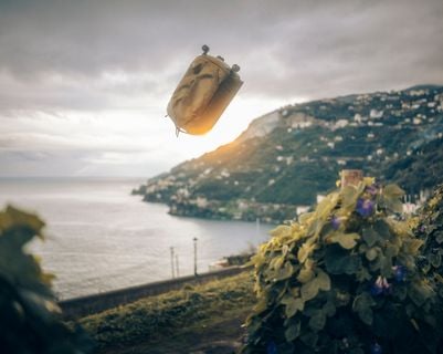 Thule Aion 가방이 석양의 아름다운 해안 풍경을 배경으로 공중에 떠 있는 듯한 모습을 연출합니다.