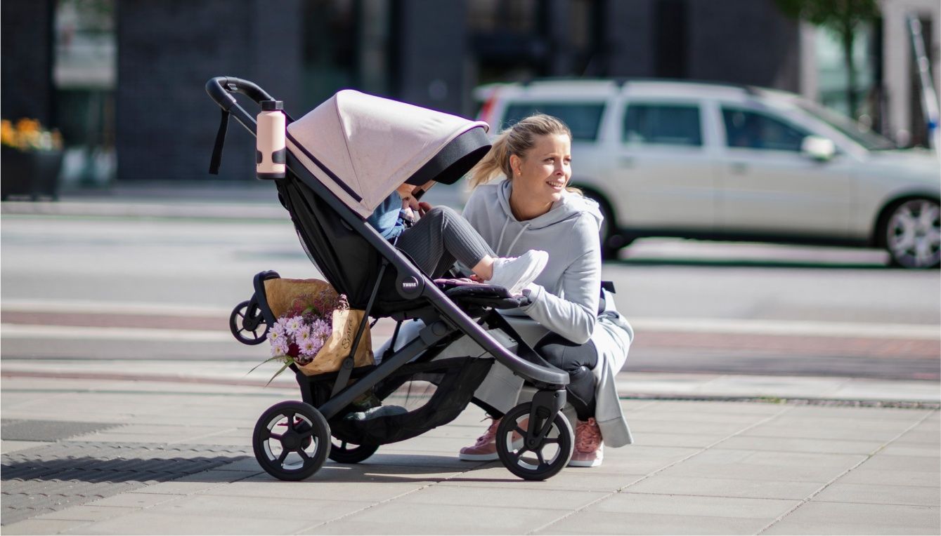 A mother kids beside her kid in a kid stroller with the best stroller accessories for a day out in town.