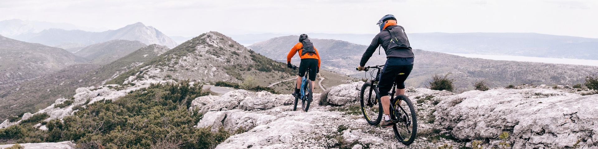 Two people cycling on mountain bikes in the mountains.