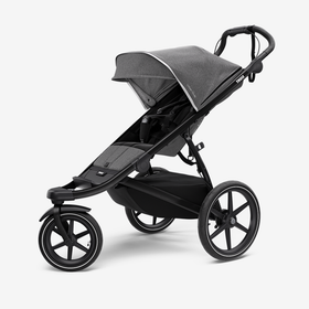 A jogging stroller that is gray with a gray background. 