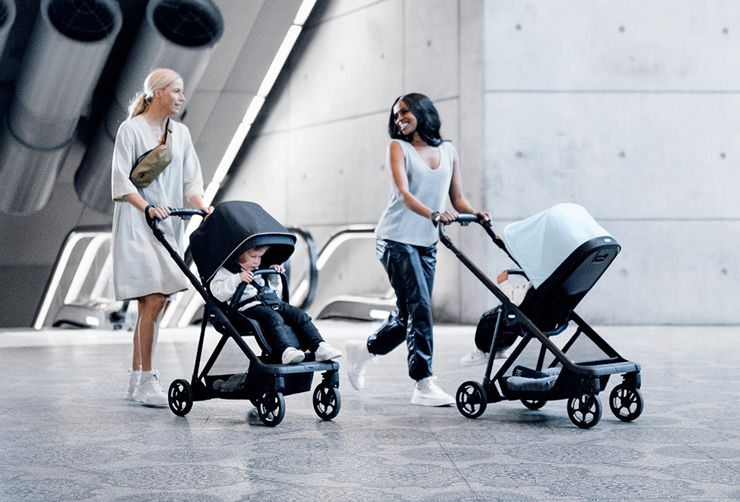 Two mothers stroll with their babies in Thule Shine strollers in a modern subway station.
