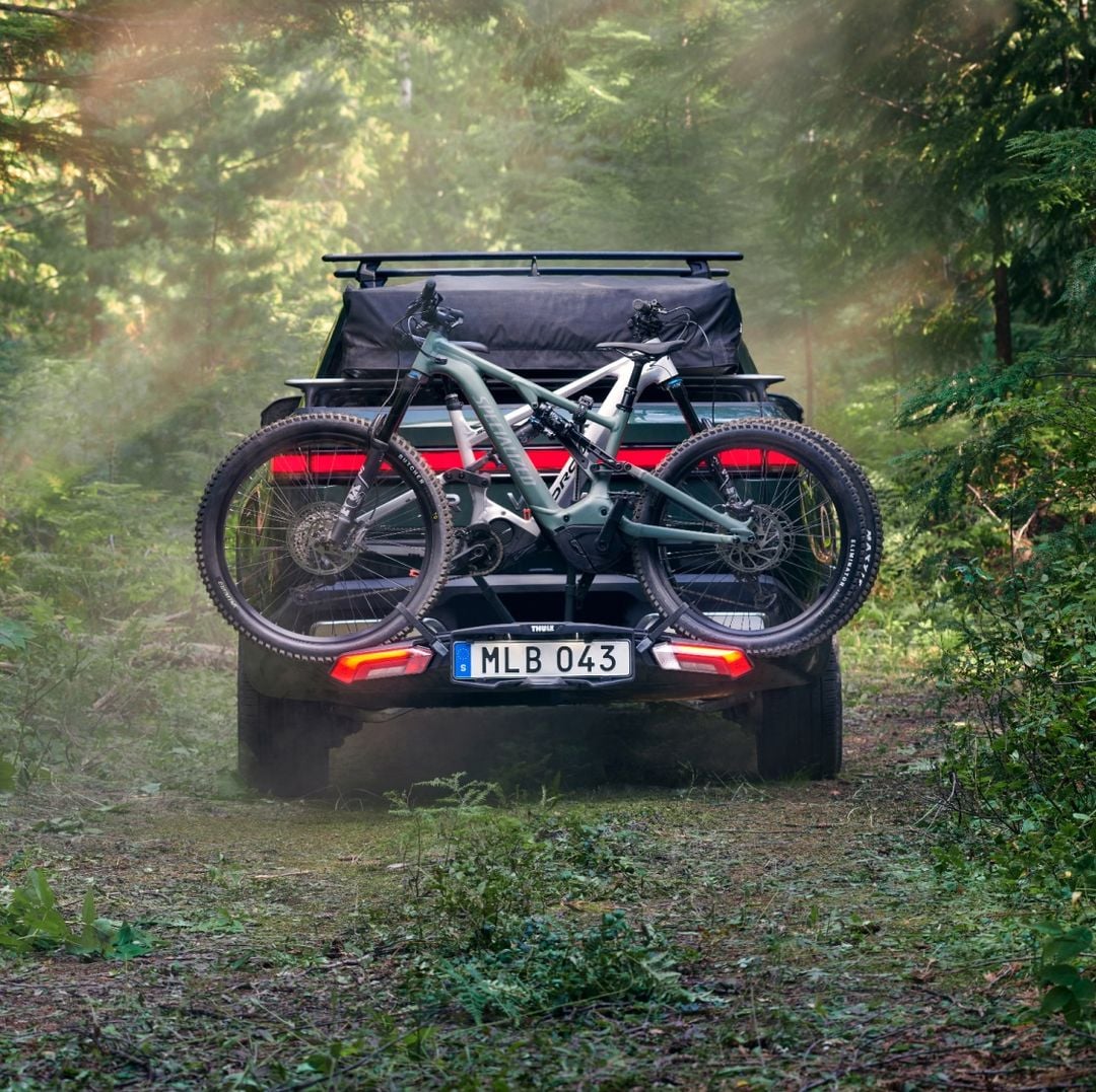 Bicikli montirani na Thule Epos stalak za bicikle na automobilu koji vozi kroz šumu.