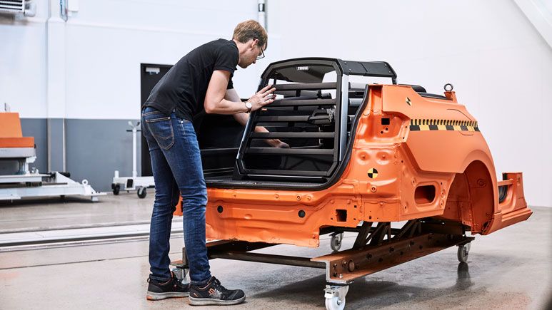 A man is mounting a Thule Allax dog crate to a crash test rig in the Thule Test Center.