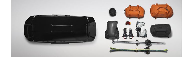 A flat lay of the Thule Motion XT roof box and the skis, ski bags, duffel bags and other items you can fit inside.
