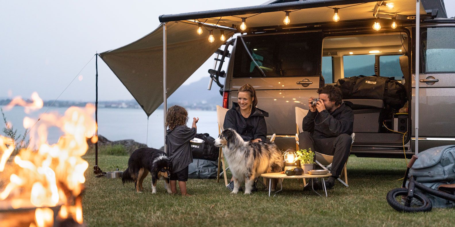 A family sit under their Thule Subsola awning panels taking pictures.