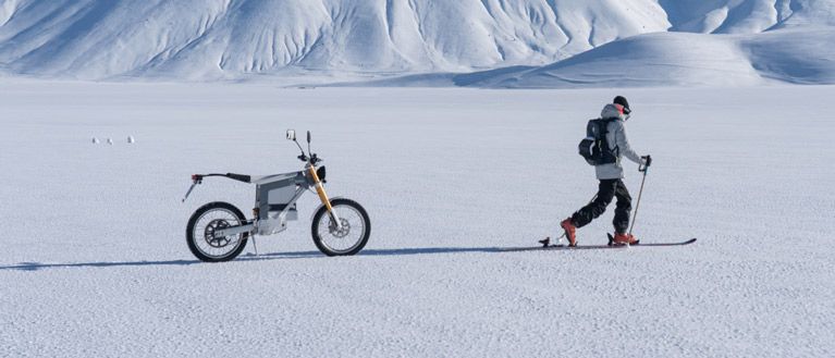 Lorenzo Alesi skiing in front of his electric motorbike with a Thule ski backpack.