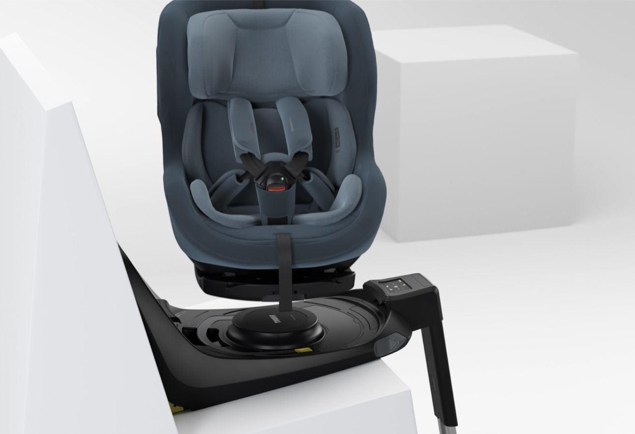 Rear-facing Thule Elm child car seat mounted on an ISOFIX base, featuring a padded headrest, five-point harness, and swivel function for easy access.