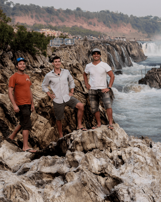 Pedro Oliva and two other men stand on a cliff above the sea.