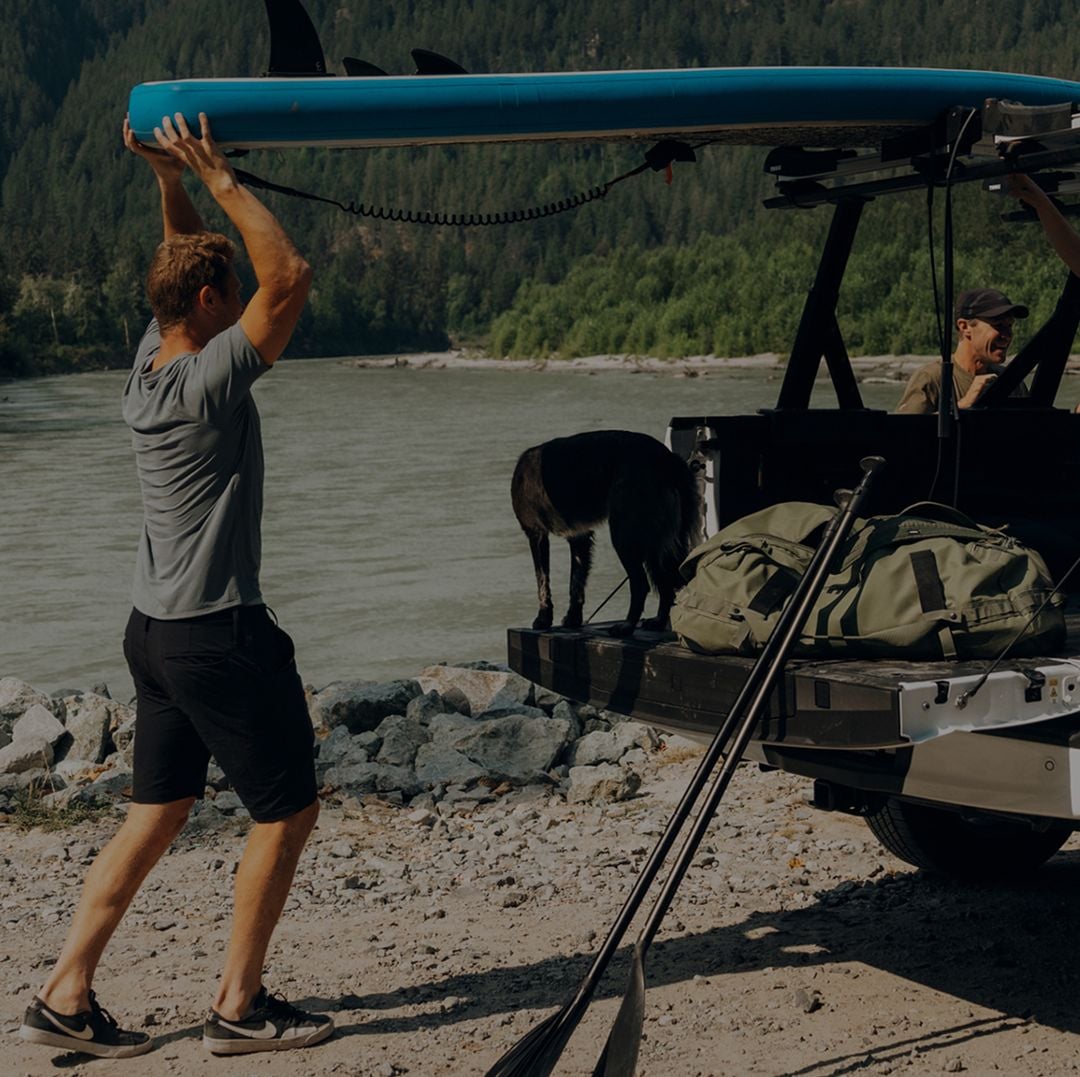 Person loading gear onto a pickup truck with a Thule Xscape truck rack.