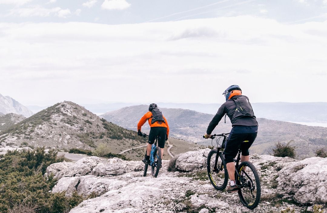 Two people cycling on mountain bikes in the mountains.