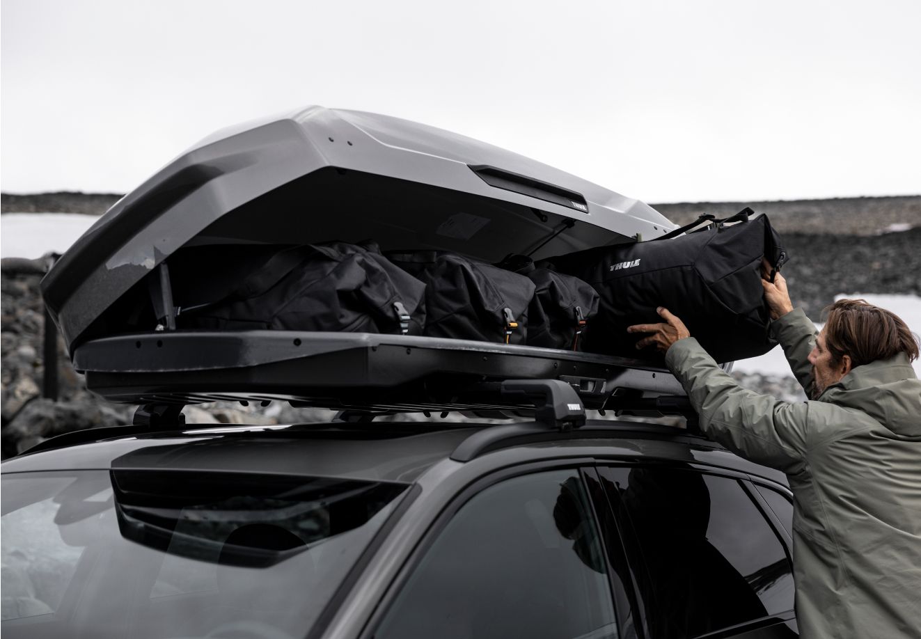En mand laster Thule GoPack-tasker op i en Thule Motion 3-tagboks.
