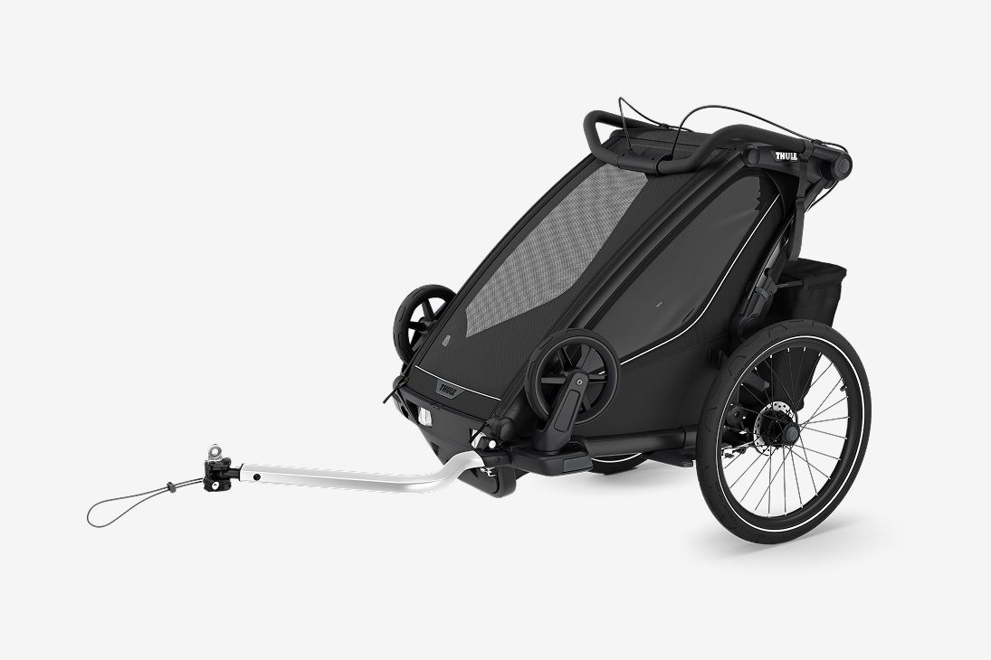 Must Thule Chariot Sport 2 jalgrattahaagis seisab helehallil taustal. 