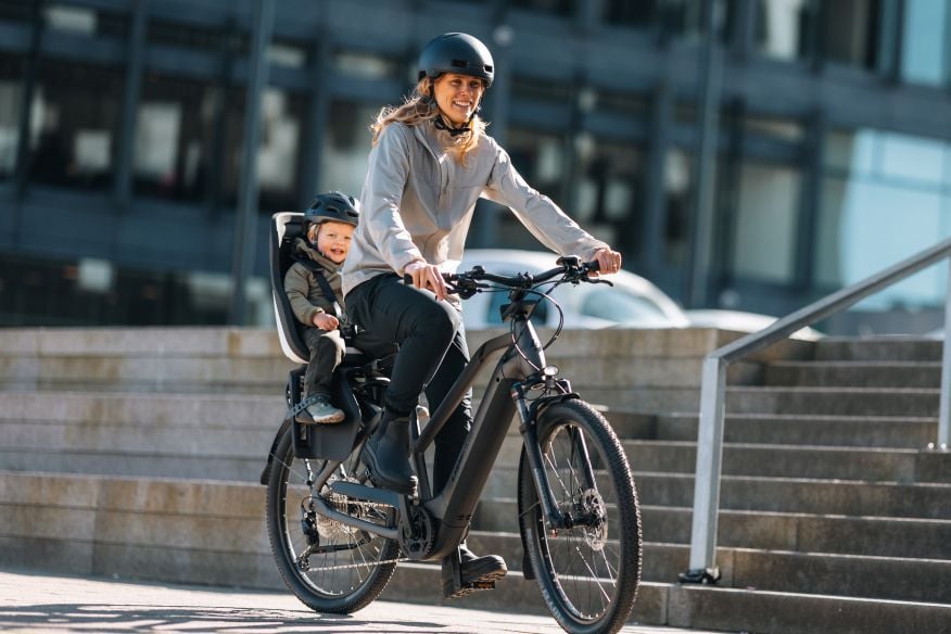 Persona en bicicleta eléctrica con un niño sentado en el trasero.