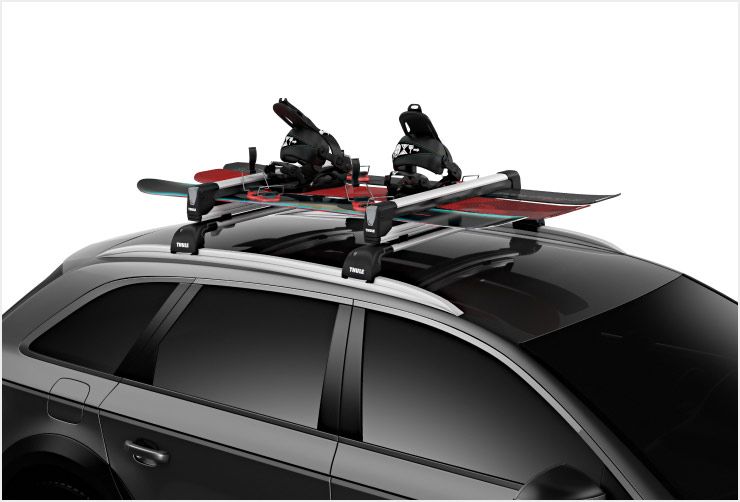 A zoomed in picture of Thule SnowPack snowboard racks mounted to the roof of a car.