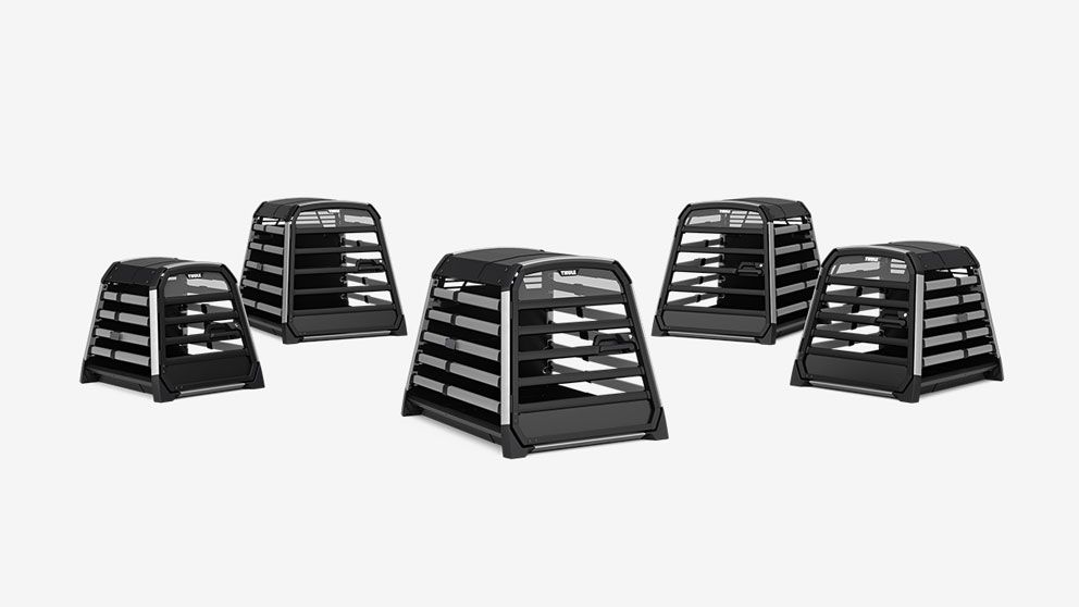 A lineup of Thule Allax dog crates in various sizes on a gray background.