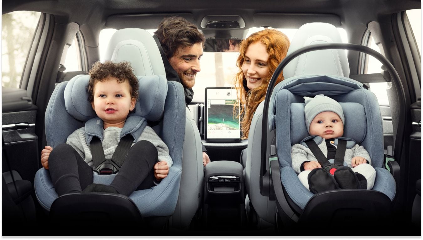 Mees ja naine, kes istuvad auto esiistmetel, pöörasid ringi, et vaadata oma lapsi, kes istuvad seljaga sõidu suunas Thule Maple laste turvaistmel ja sinises Thule Elm väikelapse turvatoolis.