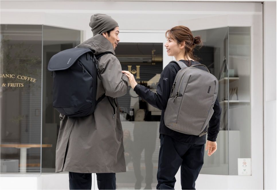 Man and woman stand outside of a café with Thule Subterra backpacks.