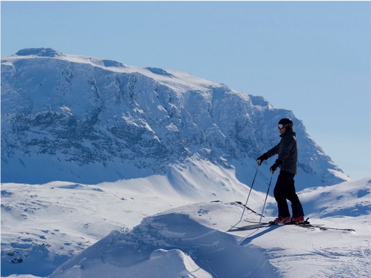 A skier stands in front of a mountain peak at the Riksgransen ski resort in Sweden.