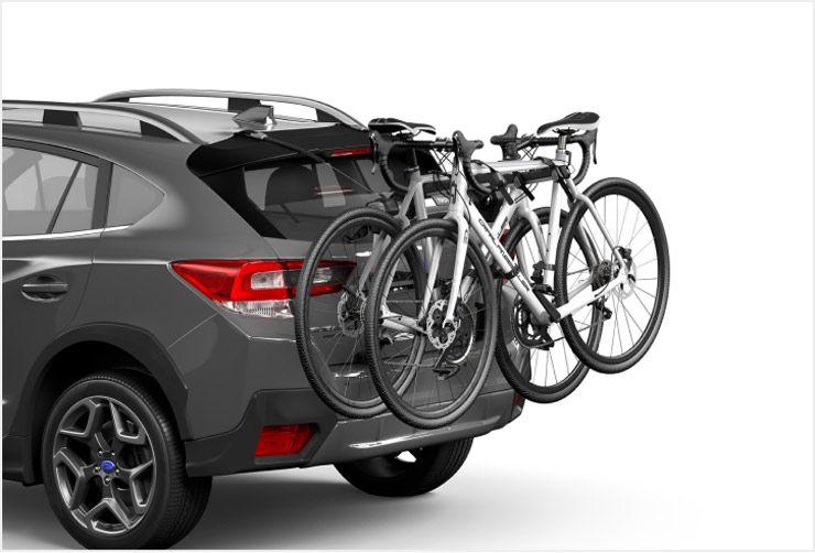 A car with a Thule trunk bike rack installed and two bikes loaded.
