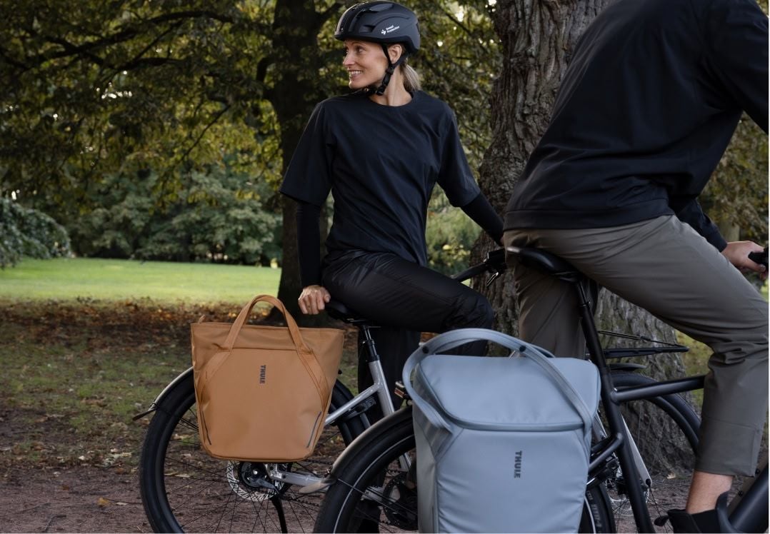 Two cyclists using bags mounted with the InLock pannier system by Thule.