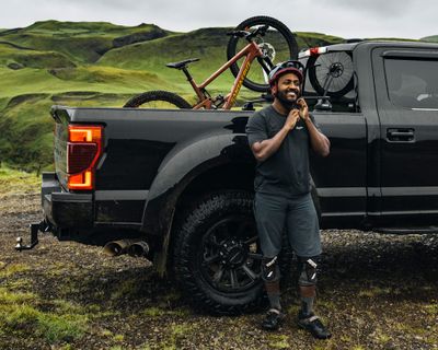 Eliot Jackson se coloca el casco al lado de una camioneta con un portabicicletas para caja de camioneta y una bicicleta.