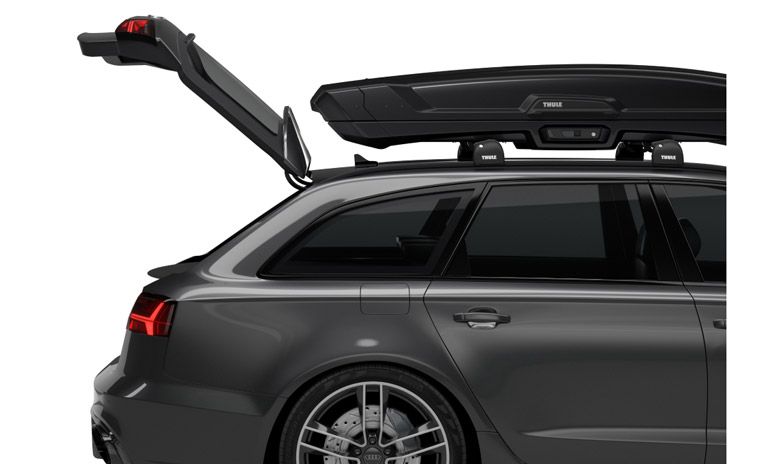 A close-up of a car with a hatch that is open even with a Thule rooftop cargo carrier on the roof.