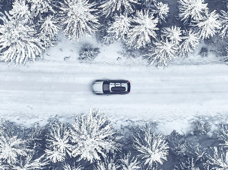 Vehicle with cargo box driving through winter forest