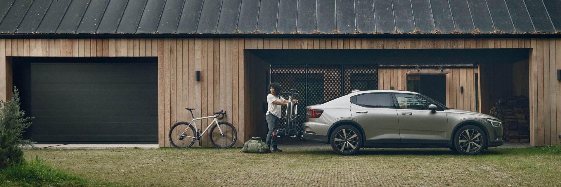 Uma mulher está perto de um suporte de bicicletas Thule montado em um carro com uma bicicleta carregada.