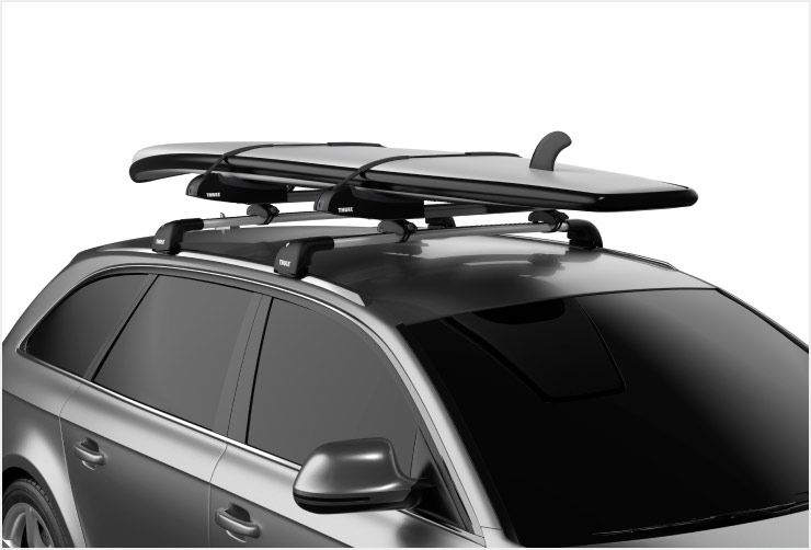 A zoomed in picture of a Thule Thule SUP Taxi XT paddle board rack mounted on the roof of a car.
