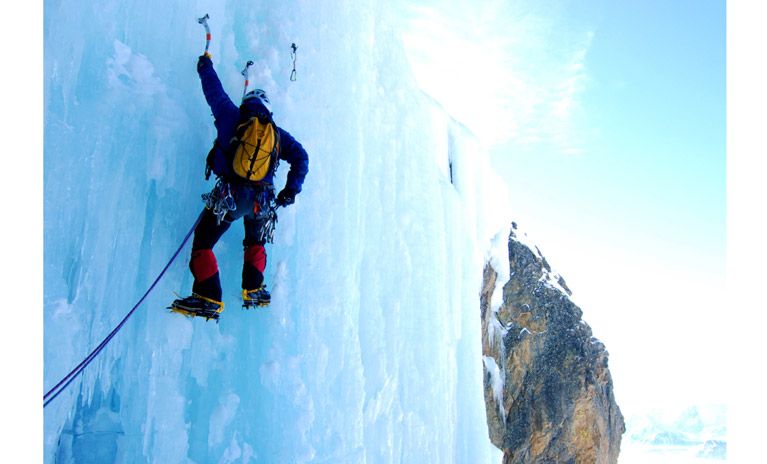 A man goes ice climbing in France on a massive ice wall.