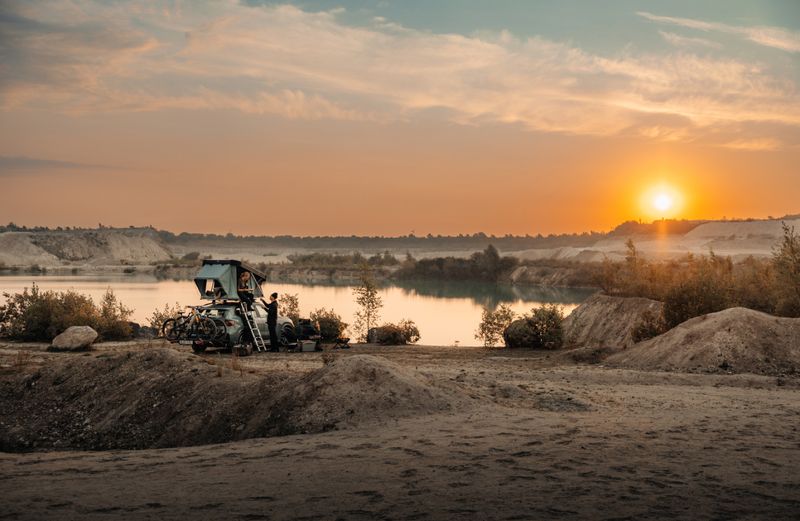 Een man en een vrouw maken een tent en een campingplaats op het dak van een auto klaar voor de nacht.