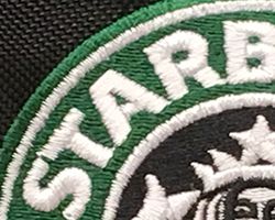 Close-up of a embroidered logo on a black backpack.