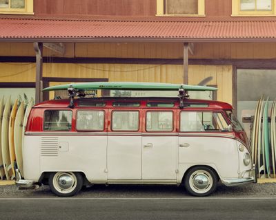 En varebil parkert med et surfebrett på taket på et surfebrettakstativ.