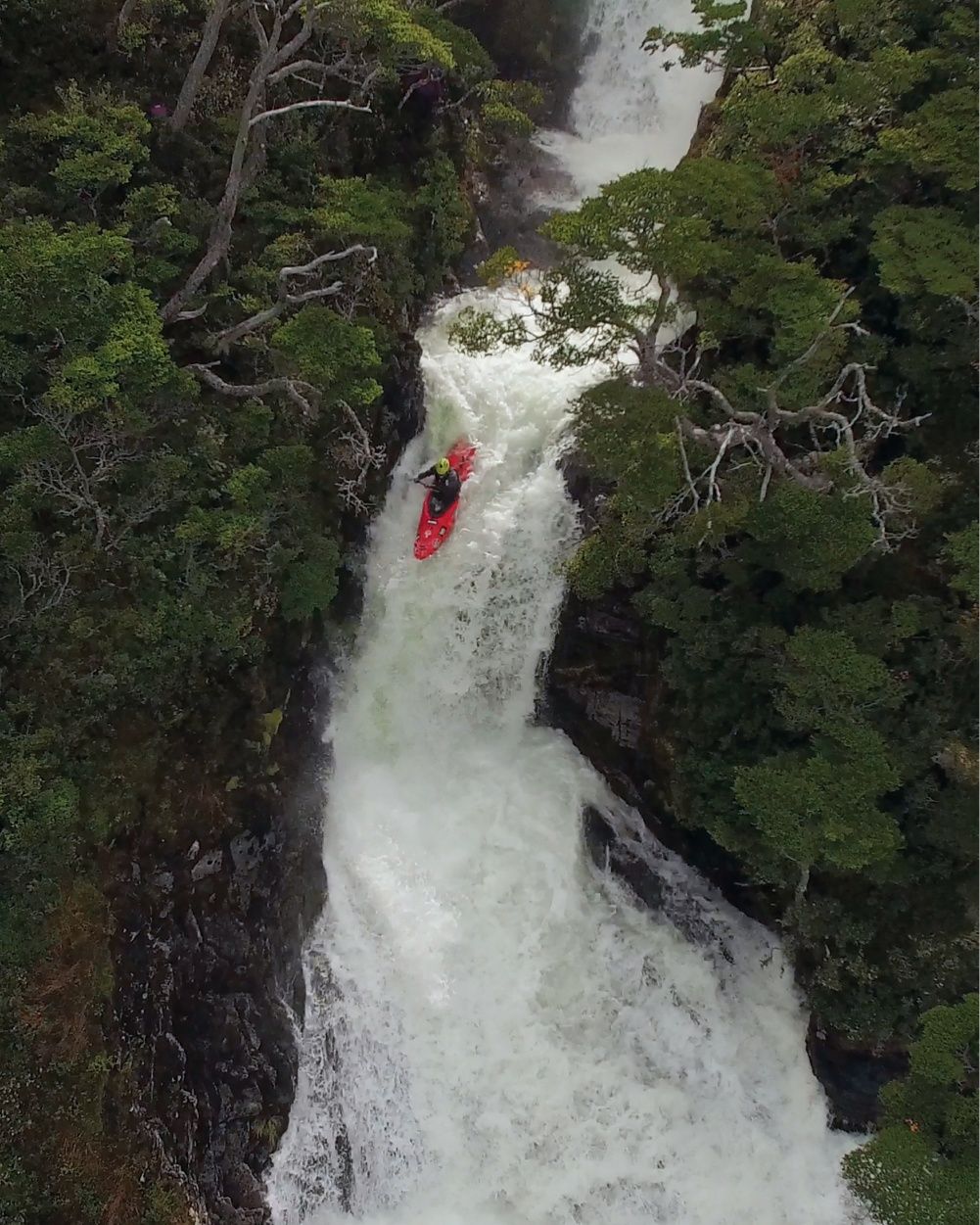 A person in a red kayak descends on a waterfall.