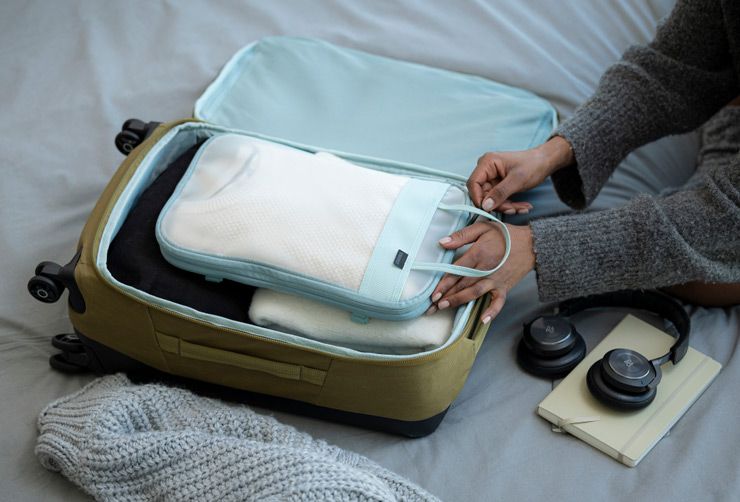 A close-up of a woman packing a compression packing cube in the Thule Aion carry on suitcase.