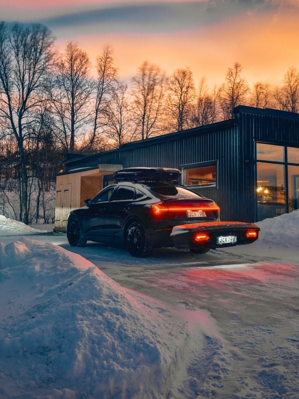 Zaparkované auto před domem, naložené nákladním vozidlem Thule jak na střeše, tak za autem.