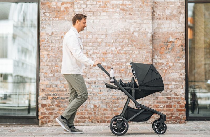A man is walking with a Thule Sleek 2 stroller in the colour black