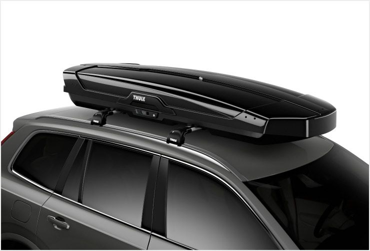 A zoomed in picture of a Thule Motion XT Alpine ski box mounted on the roof of a car.