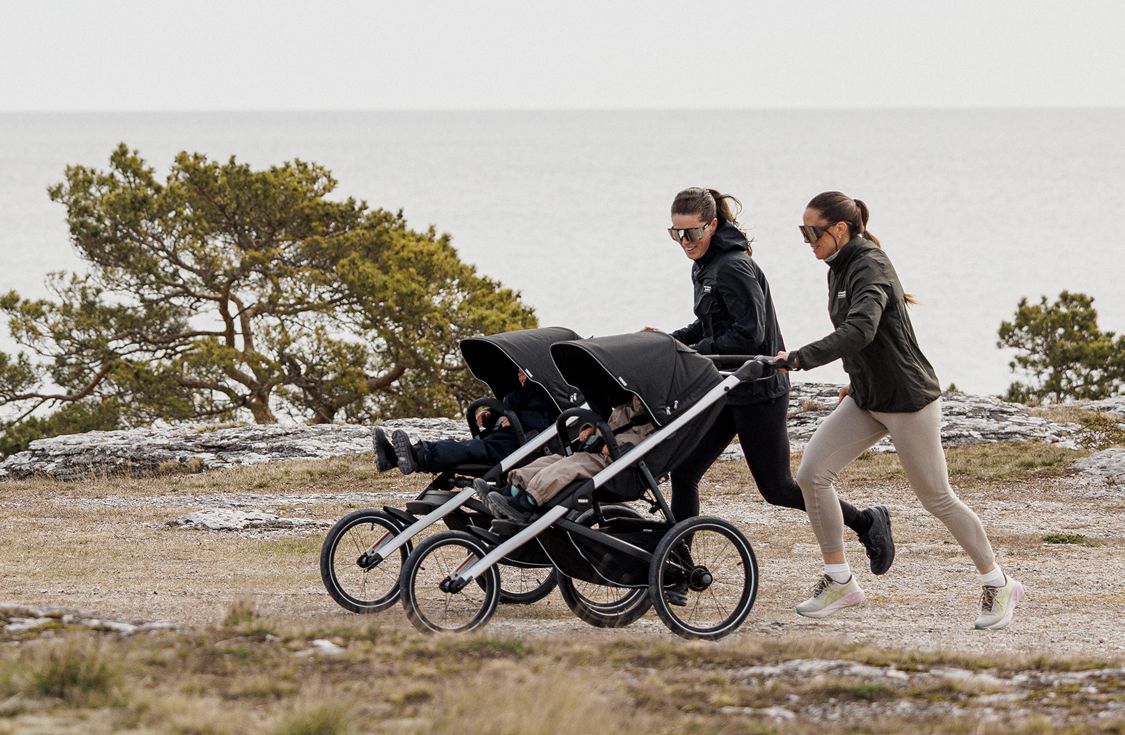 Kaks täiskasvanut jooksmas lastega Thule Glide'is 3 jooksuvankriga.