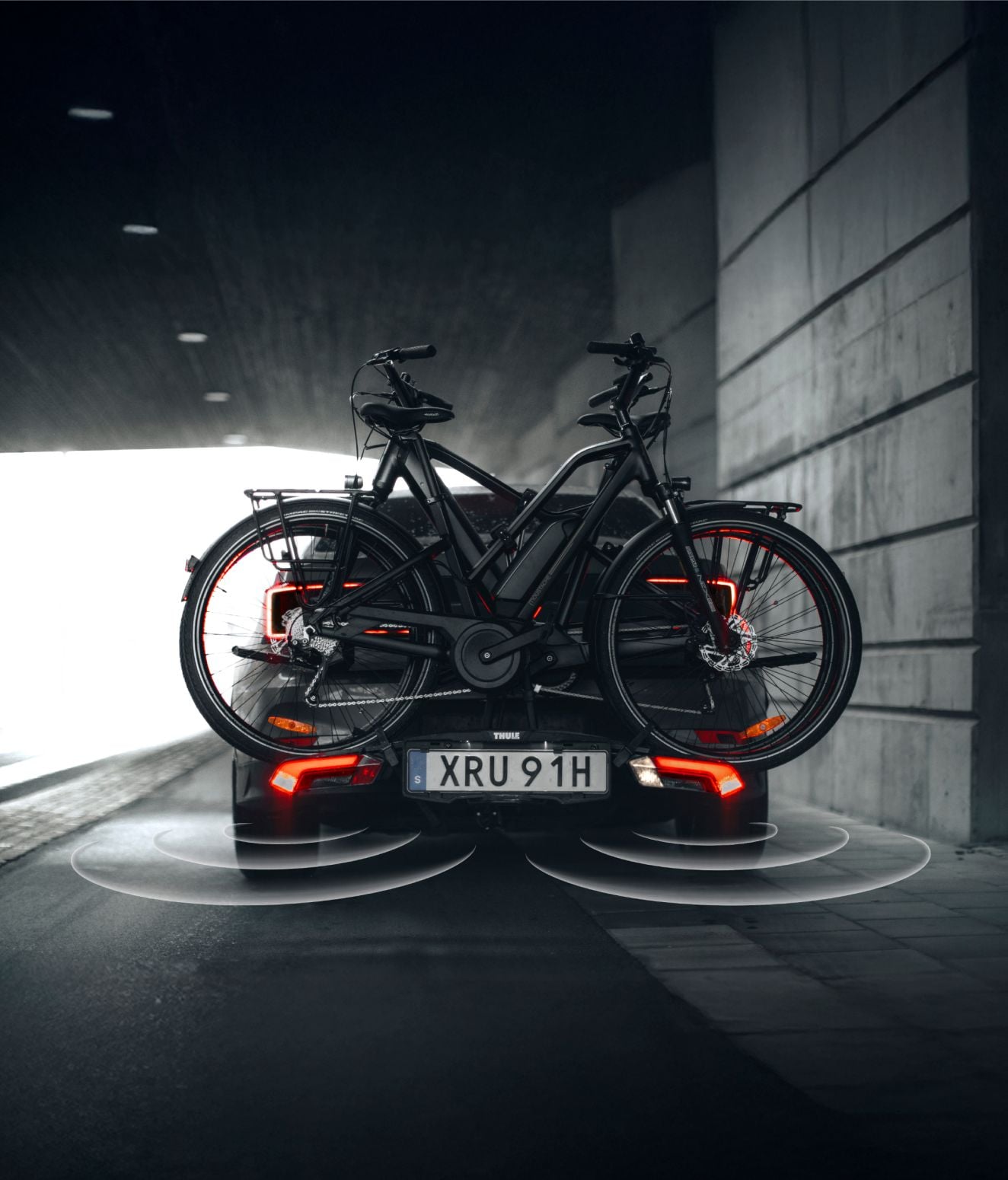 Två cyklar monterade på ett Thule Epos-cykelställ på baksidan av en bil som körde genom en tunnel.